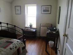 a bed room with a neatly made bed next to a window and a wooden floor