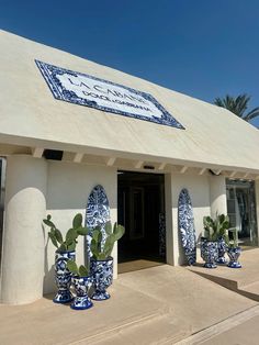 several blue and white vases with plants in front of a building that has a sign on it