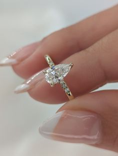 a woman's hand holding an engagement ring with a diamond on the middle finger