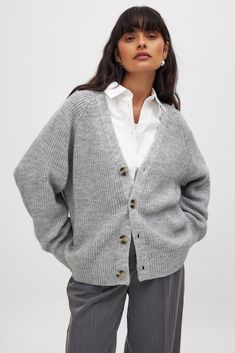 This cardigan features an oversized fit and a stretchy, soft knit material. It has a v neckline and a button closure down the front. Soft Knit V-neck Cardigan For Daywear, Cozy V-neck Cardigan For Daywear, Cozy Gray V-neck Outerwear, Gray Soft Knit V-neck Sweater, Knit V-neck Outerwear For Daywear, Casual V-neck Sweater Coat For Daywear, Trendy V-neck Cardigan For Daywear, Gray Knitted V-neck Outerwear, V-neck Soft Knit Cardigan For Daywear