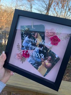 a person holding up a framed photo with flowers on it and the words, i love you