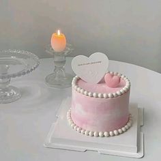 a pink cake on a white table with a candle