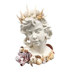 a white statue with shells on it's head and other seashells around it