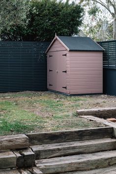 a pink shed sitting in the middle of a yard