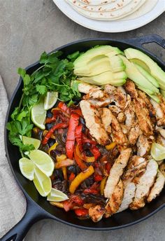 a skillet filled with chicken, peppers, avocado and cilantro