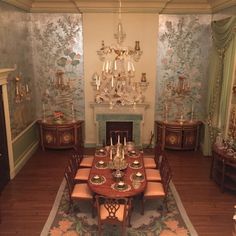 a dining room with a table, chairs and chandelier in the middle of it