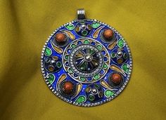 Magnificent vintage handmade Sterling Silver Kabyle pendant, enamelled in blue, green and yellow and inlaid with real coral beads. ✓ Width: 5 cm. ✓ Height: 5.3 cm. ✓ Material: Sterling Silver, coral. ✓ Weight: 20.6 grams. ✓ Origin: greater Kabylie region 1990s. ✓ Shipping will always be via DHL free of charge. ✓ Shipping within the USA 3 to 7 business days. ✓ Shipping to Europe 3-5 business days. ✓ Shipping to Japan 5 to 7 business days I have been working in the craft industry for 30 years and Artisan Jewelry With Large Pendant For Festivals, Artisan Large Pendant Jewelry For Festivals, Bohemian Jewelry With Large Pendant And Round Beads, Unique Blue Jewelry For Festivals, Multicolor Pendant Necklace For Festivals, Multicolor Pendant Necklaces For Festivals, Enamel Jewelry For Festivals And Gifts, Round Festival Necklaces With Large Pendant, Large Pendant Jewelry For Festival