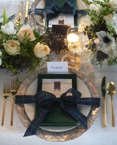 the table is set with white and green flowers, silverware, and napkins