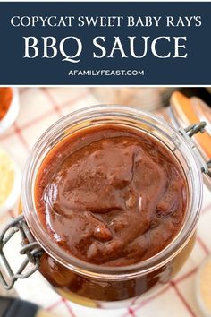 a jar filled with bbq sauce sitting on top of a table next to other food