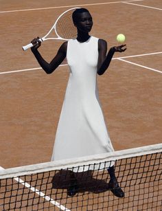 a woman holding a tennis racquet on top of a tennis court with a ball in her hand