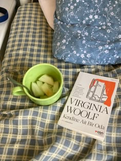 there is a bowl with apples in it and a book on the bed next to it