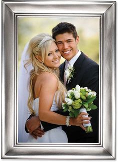 a man and woman are posing for a wedding photo in front of a silver frame