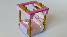 a pink and yellow dollhouse bed made out of legos on a white surface