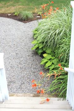 an open door leading to a garden with flowers and plants in the foreground, next to a white picket fence