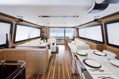 the inside of a boat with tables and couches on each side in front of windows