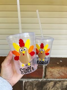 someone holding up two cups with turkey designs on them