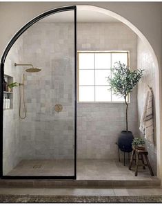 an arched glass shower door in a bathroom with white tile and black trimmings