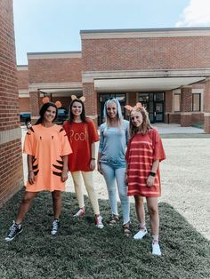 three girls in costumes standing next to each other on the grass outside of a building