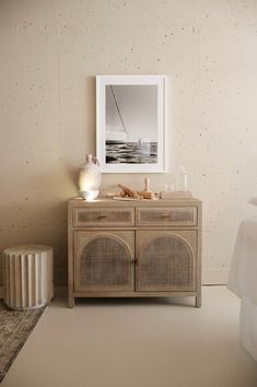 a white vase sitting on top of a wooden cabinet