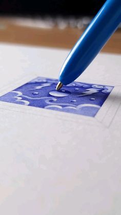 a blue pen is on top of a piece of paper that has a square design