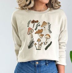 These mushroom sweatshirts are perfect all year round! They are great for layering. These sweatshirts are 50% pre-shrunk cotton, 50% polyester.  Wash on cold, dry inside out. Do not iron over design.  Processing time is 7-10 business days plus an additional 2-5 business days for standard shipping. Please message me if you need it sooner and I can see if I have the inventory on hand already. Cotton Fall Sweatshirt With Mushroom Print, Cotton Sweatshirt With Mushroom Print For Fall, Casual Fall Sweatshirt With Mushroom Print, Cotton Crew Neck Sweatshirt With Mushroom Print, Casual Crew Neck Sweatshirt With Mushroom Print, Relaxed Fit Fall Tops With Mushroom Print, Casual Mushroom Print Sweatshirt For Fall, Casual Long Sleeve Top With Mushroom Design, Relaxed Fit Top With Mushroom Print For Fall