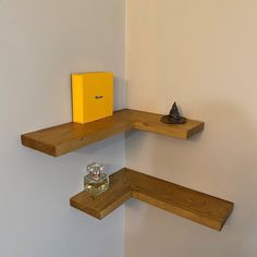 two wooden shelves with small items on them in a corner next to a wall and a yellow box