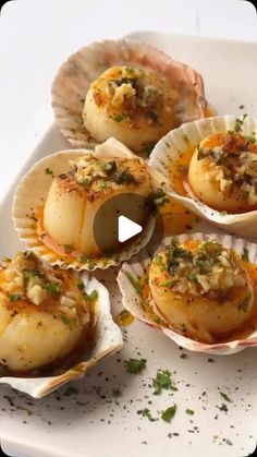 several scallops with various toppings on a white platter, ready to be eaten