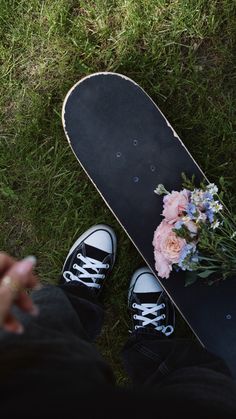 a skateboard with flowers on the ground next to someone's feet and shoes