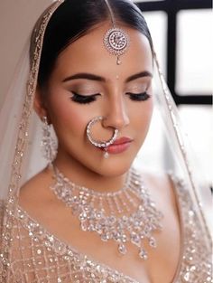 a woman in a bridal outfit with jewelry on her face and nose ring around her neck