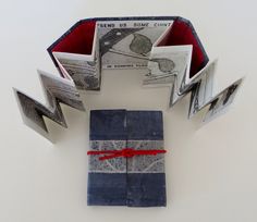 an open book sitting on top of a table next to two folded up books with red ribbon