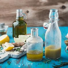 bottles filled with different types of ingredients on top of a blue table next to garlic and pepper