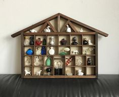 a doll house made out of wooden shelves filled with bottles and figurines on top of a black leather couch