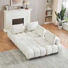 a white couch sitting on top of a hard wood floor next to a fire place