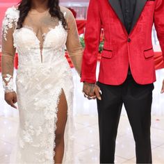 a man and woman standing next to each other in front of a red wall with white lights