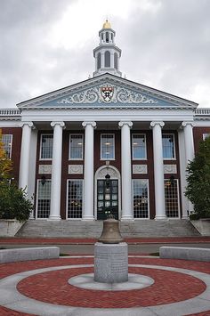 an old building with a clock tower and bell on top in front of a red brick courtyard