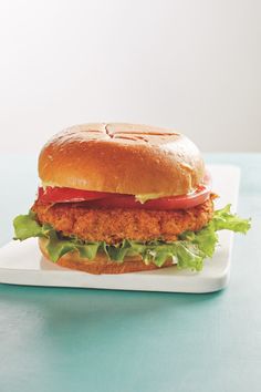 a chicken sandwich with lettuce, tomato and mayonnaise on a white plate