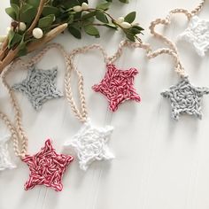 crocheted stars are hanging from twine on a white table next to flowers