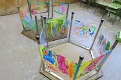 three children's chairs with colorful paintings on them in the middle of a room