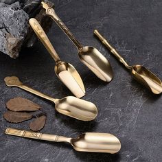 gold colored utensils and spoons sitting on a black stone countertop next to rocks