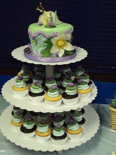 a three tiered cake with cupcakes on it