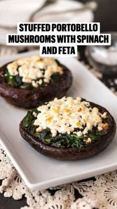 two stuffed mushrooms with spinach and feta cheese are on a square white plate