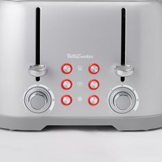 a silver toaster sitting on top of a white counter next to two red knobs