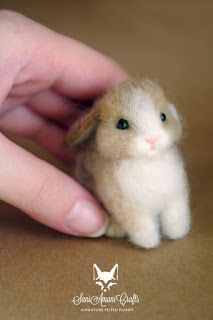 a hand is holding a tiny stuffed animal