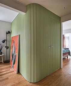 a room with a green wall and wooden flooring in the corner, next to a bed