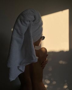 a woman with a towel on her head and sun shining through the window behind her