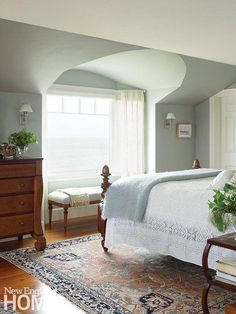 a bed sitting in a bedroom next to a wooden dresser and lamp on top of a hard wood floor