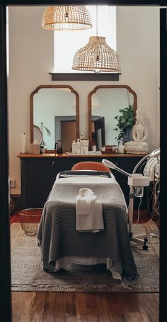 a room with a bed, mirror and lights hanging from it's ceiling in front of two mirrors