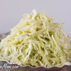 a bowl filled with shredded cabbage on top of a checkered tablecloth covered table