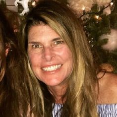 two women are smiling in front of a christmas tree