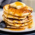 a stack of pancakes with syrup and blueberries on a plate